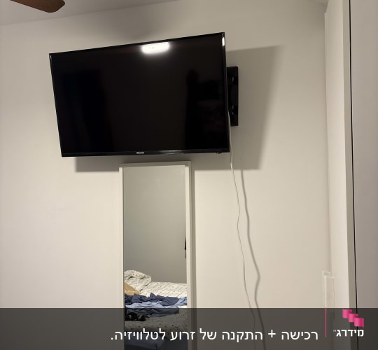 טלוויזיה תלויה על הקיר עם כבל חשמל
